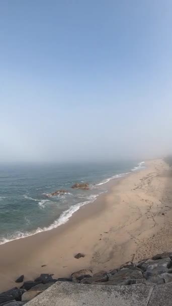 Kilátás az Atlanti-óceánra. Üres strand Povoa de Varzim, Portugália a Ködös őszi nap hullámok összeomlik a parton és a köd a távolban. — Stock videók