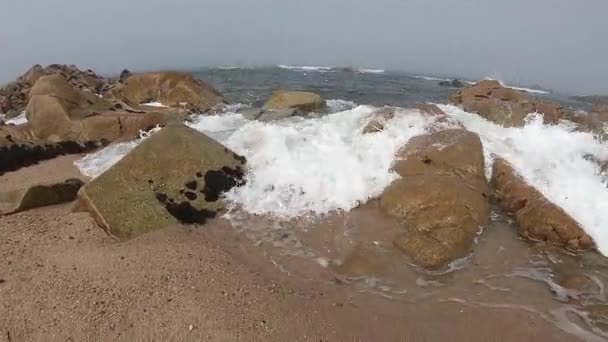 Vista para o Oceano Atlântico. Praia vazia em Povoa de Varzim, Portugal, no dia nebuloso do Outono, com ondas a despenharem-se na costa por baixo e nevoeiro à distância. Água batendo contra pedras na costa . — Vídeo de Stock