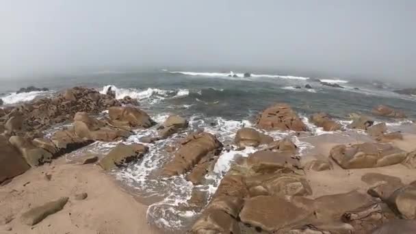 Kilátás az Atlanti-óceánra. Üres strand Povoa de Varzim, Portugália a Ködös őszi nap hullámok összeomlik a parton és a köd a távolban. Víz ellen a kövek a parton. — Stock videók