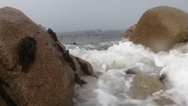 Vedere spre Oceanul Atlantic. Plaja goală din Povoa de Varzim, Portugalia, în ziua de toamnă cețoasă, cu valuri care se prăbușesc pe țărm și ceață la distanță. Apa bate împotriva pietrelor de pe țărm . — Videoclip de stoc