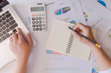 Kadın elini hesap makinesi kullanarak kapat ve not al. Ev ofisinin maliyetini hesapla..