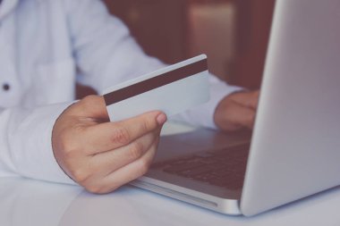 Kredi kartı tutan ve online ödeme online, online alışveriş yapma dizüstü kullanarak adam el