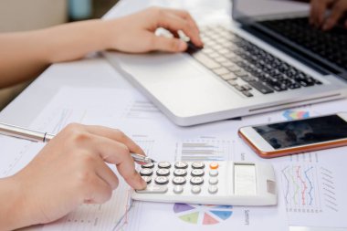 hesap makinesi ve dizüstü ekonomi ofisinde yapmakla kağıt grafik verilerini kullanarak kadın kapatmak.