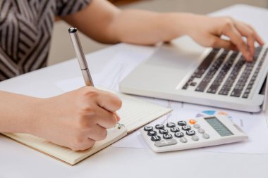 Kadın el yazma yapmak Not ve dizüstü ekonomi ofisinde yapmakla kağıt grafik verilerini kullanma.