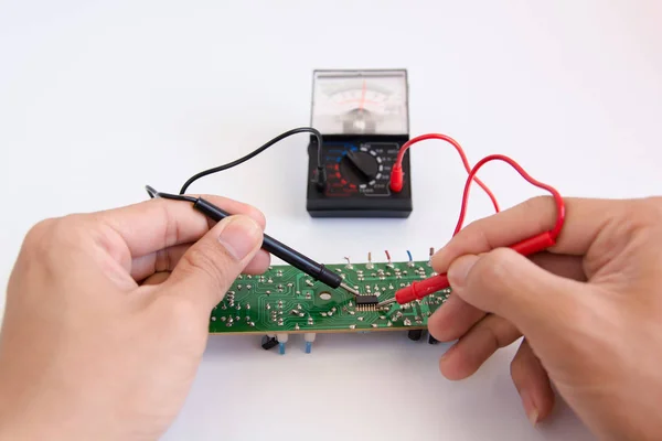 Technician hand with multimeter probes repairing circuit board