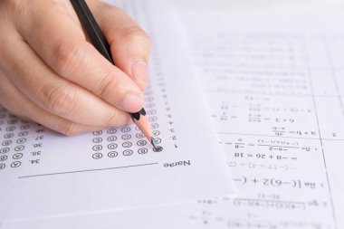 Öğrenciler, cevap kağıtları ve matematik soru kağıtları üzerinde seçilmiş kalemle yazı yazma seçeneğini el ele tutuyorlar. Sınav yapan öğrenciler. okul sınavı 