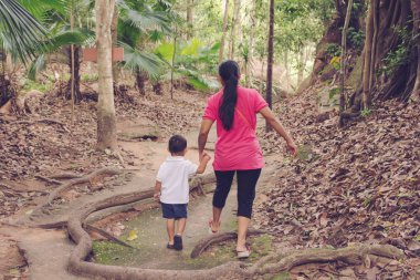 Anne oğlu kızı bir el tutarak kamu parkta yürümek