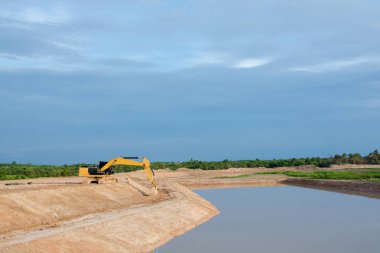 Sarı ekskavatör makinesi inşaat alanında nehir kenarı hareketli toprak taşıma işleri