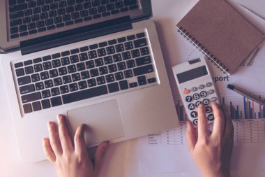 ofiste finans yaparak kağıt grafik verileri üzerinde hesap makinesi ve dizüstü bilgisayar kullanarak kadın yakın. üst görünüm