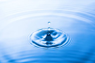 Suya düşen su damlası dalgalar yapar. Su sıçraması veya su damlası arka plan. 