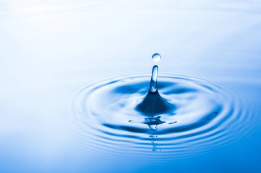 Suya düşen su damlası dalgalar yapar. Su sıçraması veya su damlası arka plan. 