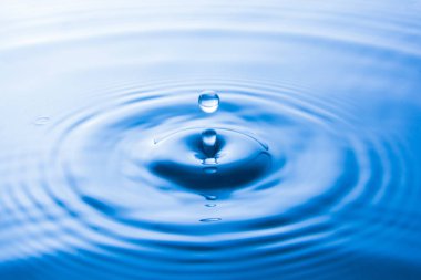 Suya düşen su damlası dalgalar yapar. Su sıçraması veya su damlası arka plan. 