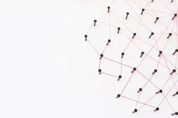 Linking entities, social media, Communications Network, The connection between the two networks. Network simulation on white paper linked together created by black nail and red thread with copy space