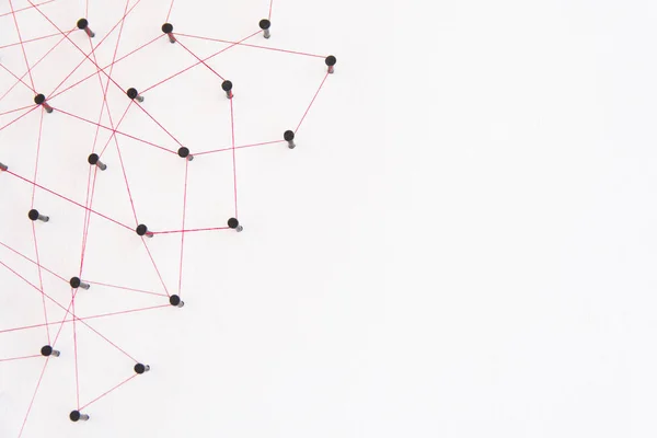 Linking entities, social media, Communications Network, The connection between the two networks. Network simulation on white paper linked together created by black nail and red thread with copy space