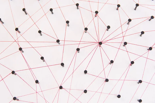 Linking entities, social media, Communications Network, The connection between the two networks. Network simulation on white paper linked together created by black nail and red thread