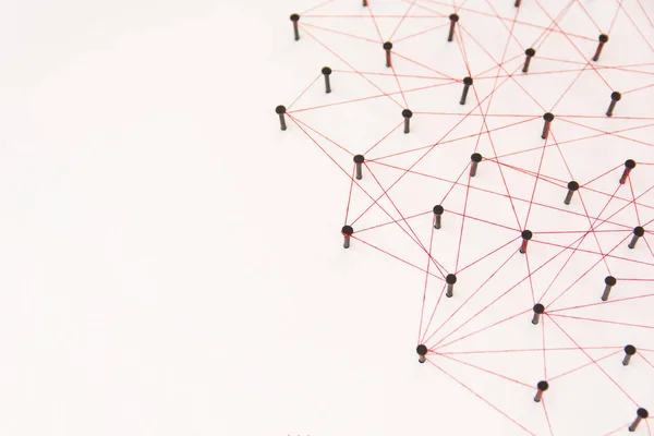 Linking entities, social media, Communications Network, The connection between the two networks. Network simulation on white paper linked together created by black nail and red thread with copy space