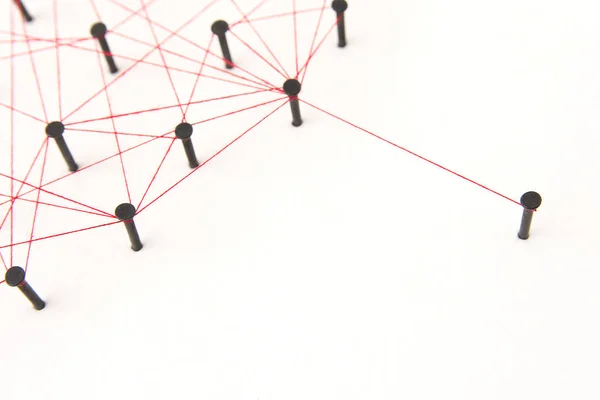 Linking entities, social media, Communications Network, one person connected to the rest networks. Network simulation on white paper linked together created by black nail and red thread with copy space