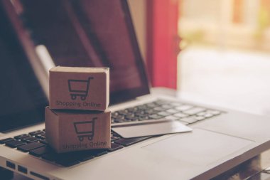 Online kavramı alışveriş - online web üzerinde hizmet alışveriş. ödeme kredi kartı ve teklifler eve teslim. bir dizüstü bilgisayar klavye logosuna parsel veya kağıt karton bir alışveriş sepeti