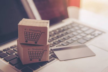 Online kavramı alışveriş - online web üzerinde hizmet alışveriş. ödeme kredi kartı ve teklifler eve teslim. bir dizüstü bilgisayar klavye logosuna parsel veya kağıt karton bir alışveriş sepeti