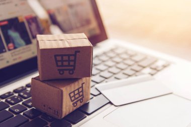 Online kavramı alışveriş - online web üzerinde hizmet alışveriş. ödeme kredi kartı ve teklifler eve teslim. bir dizüstü bilgisayar klavye logosuna parsel veya kağıt karton bir alışveriş sepeti