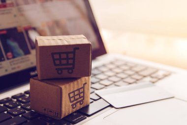 Online kavramı alışveriş - online web üzerinde hizmet alışveriş. ödeme kredi kartı ve teklifler eve teslim. bir dizüstü bilgisayar klavye logosuna parsel veya kağıt karton bir alışveriş sepeti