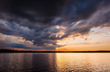 Göl günbatımı. Fırtına bulutları üzerinden yukarıda gök gürültüsü fırtına öncesi arkasında güzel gün batımı göl manzara arka plan. Gün batımında bulut ile dramatik gökyüzü.