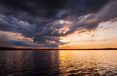 Göl günbatımı. Fırtına bulutları üzerinden yukarıda gök gürültüsü fırtına öncesi arkasında güzel gün batımı göl manzara arka plan. Gün batımında bulut ile dramatik gökyüzü.