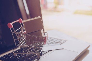 Online kavramı alışveriş - online web üzerinde hizmet alışveriş. ödeme kredi kartı ve teklifler eve teslim. bir dizüstü keyboar logosuna parsel veya kağıt karton bir alışveriş sepeti