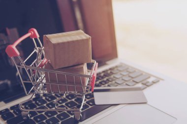 Online kavramı alışveriş - online web üzerinde hizmet alışveriş. ödeme kredi kartı ve teklifler eve teslim. bir dizüstü keyboar logosuna parsel veya kağıt karton bir alışveriş sepeti
