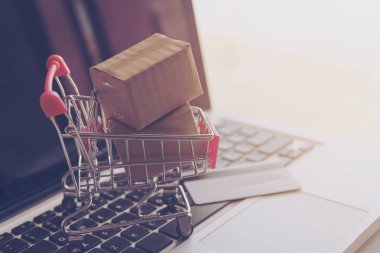 Online kavramı alışveriş - online web üzerinde hizmet alışveriş. ödeme kredi kartı ve teklifler eve teslim. bir dizüstü keyboar logosuna parsel veya kağıt karton bir alışveriş sepeti