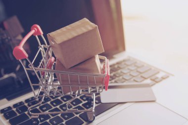 Online kavramı alışveriş - online web üzerinde hizmet alışveriş. ödeme kredi kartı ve teklifler eve teslim. bir dizüstü keyboar logosuna parsel veya kağıt karton bir alışveriş sepeti