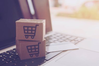 Online kavramı alışveriş - online web üzerinde hizmet alışveriş. ödeme kredi kartı ve teklifler eve teslim. bir dizüstü keyboar logosuna parsel veya kağıt karton bir alışveriş sepeti