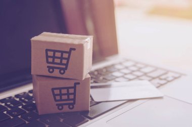 Online kavramı alışveriş - online web üzerinde hizmet alışveriş. ödeme kredi kartı ve teklifler eve teslim. bir dizüstü keyboar logosuna parsel veya kağıt karton bir alışveriş sepeti