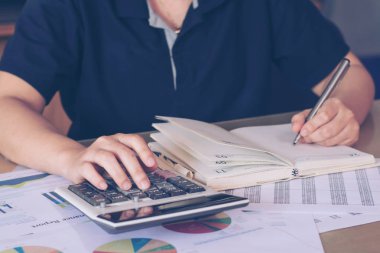 İş concep: kadın el hesap makinesini kullanarak kapatın ve yazılı notu ofis masası hesaplamak yapmak.