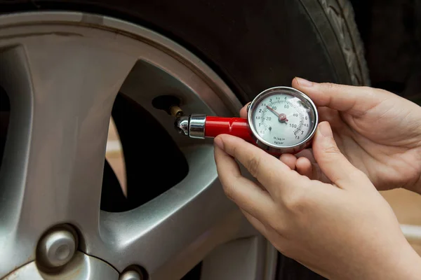 Tire pressure gauge : Hand holding pressure gauge checking air pressure for car tire. Safe driving.