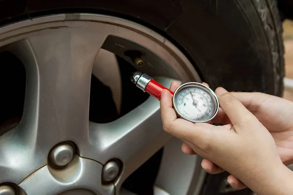 Tire pressure gauge : Hand holding pressure gauge checking air pressure for car tire. Safe driving.