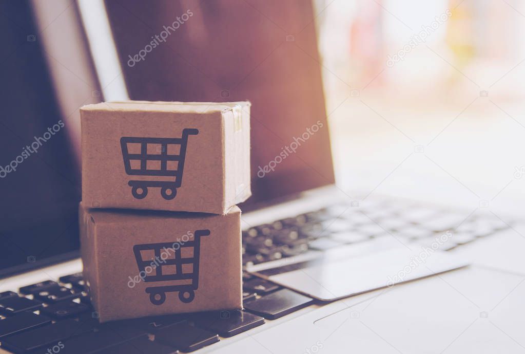 Shopping online concept - Shopping service on The online web. with payment by credit card and offers home delivery. parcel or Paper cartons with a shopping cart logo on a laptop keyboar