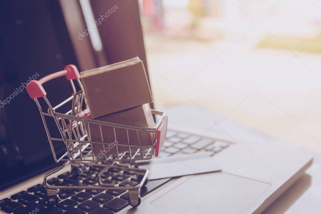 Shopping online concept - Shopping service on The online web. with payment by credit card and offers home delivery. parcel or Paper cartons with a shopping cart logo on a laptop keyboar