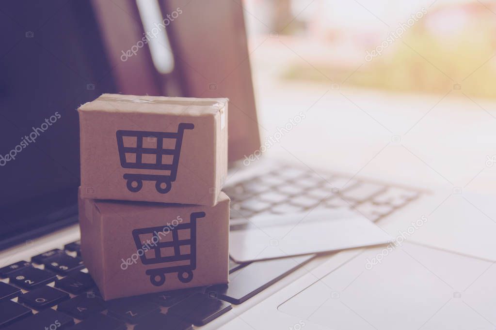 Shopping online concept - Shopping service on The online web. with payment by credit card and offers home delivery. parcel or Paper cartons with a shopping cart logo on a laptop keyboar