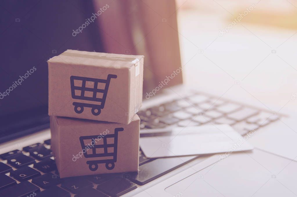 Shopping online concept - Shopping service on The online web. with payment by credit card and offers home delivery. parcel or Paper cartons with a shopping cart logo on a laptop keyboar