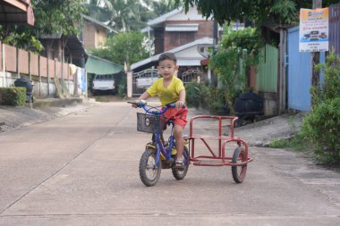  Nakhon Phanom, Tayland - 14 Eylül 2018: Çocuk yolda bir kask sürme üç tekerlekli bisiklet