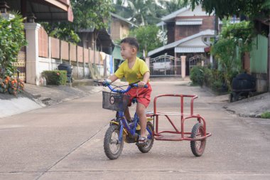  Nakhon Phanom, Tayland - 14 Eylül 2018: Çocuk yolda bir kask sürme üç tekerlekli bisiklet