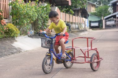  Nakhon Phanom, Tayland - 14 Eylül 2018: Çocuk yolda bir kask sürme üç tekerlekli bisiklet