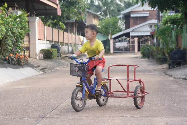  Nakhon Phanom, Tayland - 14 Eylül 2018: Çocuk yolda bir kask sürme üç tekerlekli bisiklet