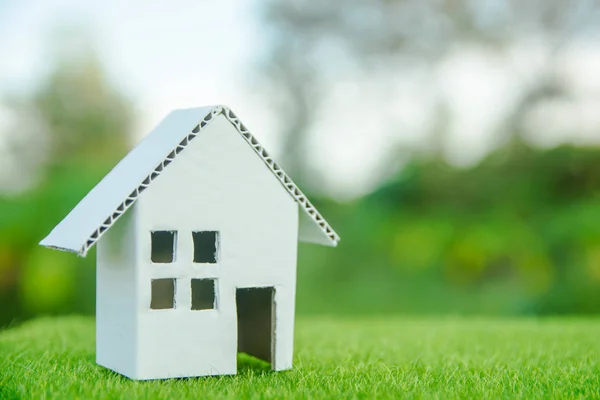 Eco house concept : Cardboard cut house on green grass with copy space