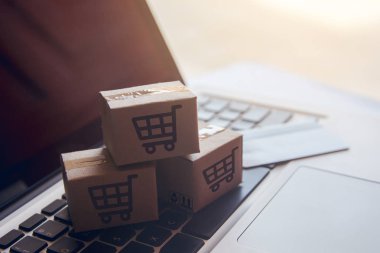 Online kavramı alışveriş - online web üzerinde hizmet alışveriş. ödeme kredi kartı ve teklifler eve teslim. bir dizüstü keyboar logosuna parsel veya kağıt karton bir alışveriş sepeti