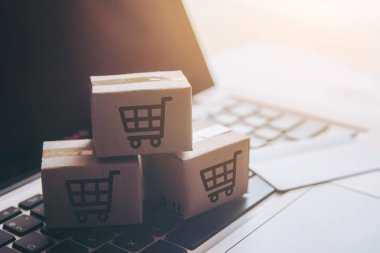 Online kavramı alışveriş - online web üzerinde hizmet alışveriş. ödeme kredi kartı ve teklifler eve teslim. bir dizüstü keyboar logosuna parsel veya kağıt karton bir alışveriş sepeti