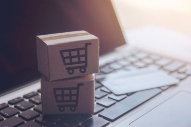 Online kavramı alışveriş - online web üzerinde hizmet alışveriş. ödeme kredi kartı ve teklifler eve teslim. bir dizüstü keyboar logosuna parsel veya kağıt karton bir alışveriş sepeti