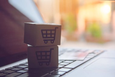 Online kavramı alışveriş - online web üzerinde hizmet alışveriş. ödeme kredi kartı ve teklifler eve teslim. bir dizüstü keyboar logosuna parsel veya kağıt karton bir alışveriş sepeti