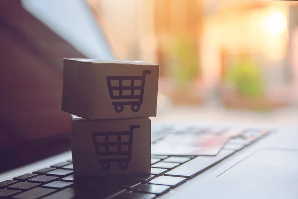 Shopping online concept - Shopping service on The online web. with payment by credit card and offers home delivery. parcel or Paper cartons with a shopping cart logo on a laptop keyboar